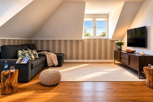 Una sala de estar moderna con sofá, reposapiés y mueble para el equipo de entretenimiento.