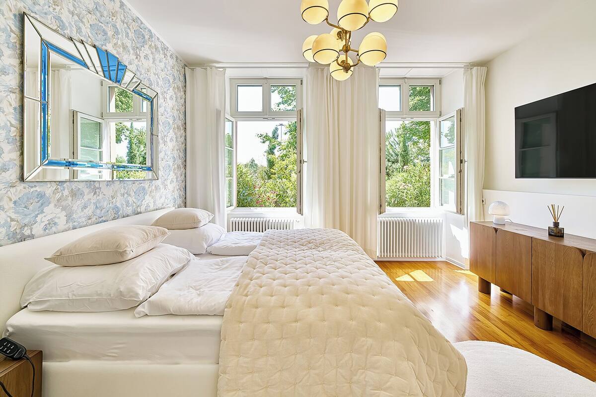 Ein Schlafzimmer mit einem großen Bett, einem Schminktisch, einem Spiegel und einem Fernseher.