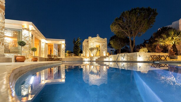 A swimming pool with stone architecture and outdoor seating. - Villa Pela (Paros)