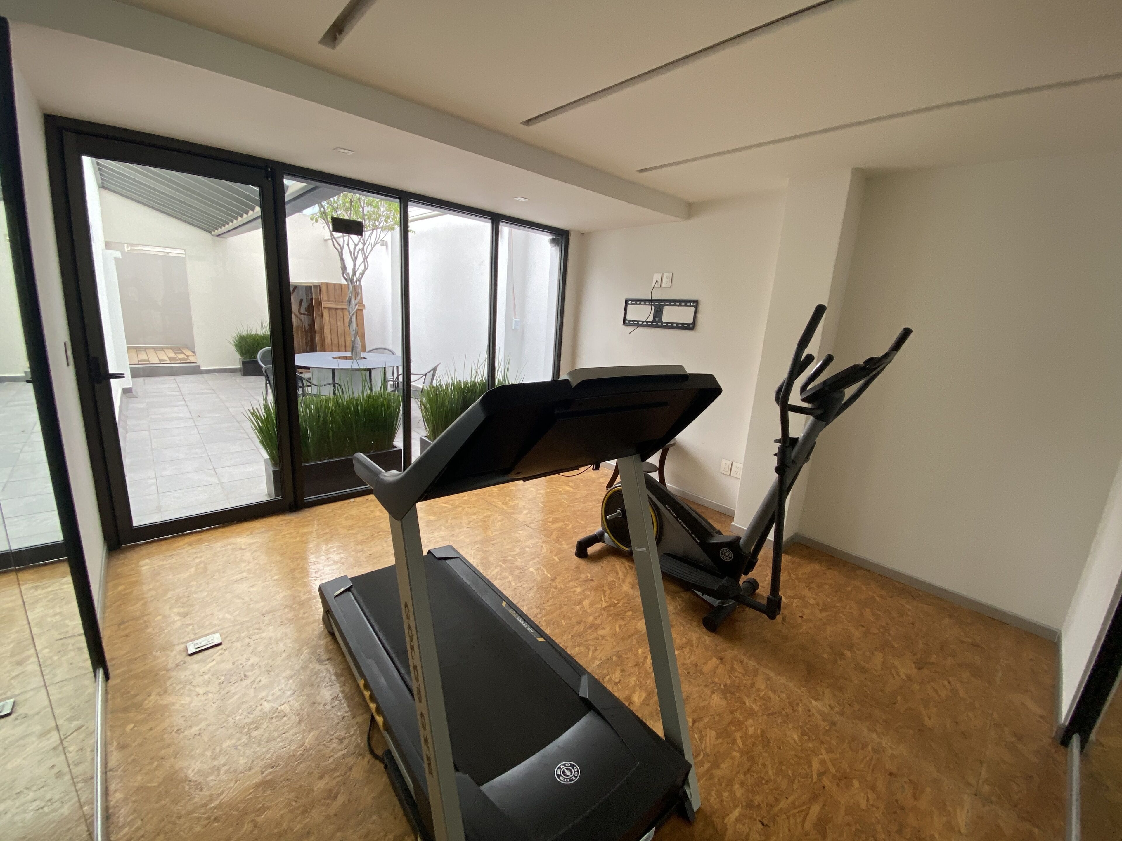 A modern home gym with a treadmill, elliptical, and exercise bike.
