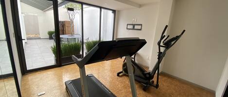 A modern home gym with a treadmill, elliptical, and exercise bike.