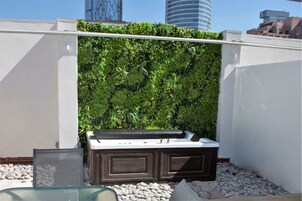 Une terrasse sur le toit agrémentée d’un mur végétal, d’un espace salon avec un banc rembourré et d’une petite table.