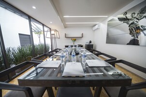 Une salle de conférence moderne avec une table en verre, des bouteilles d’eau et un vase de fleurs.
