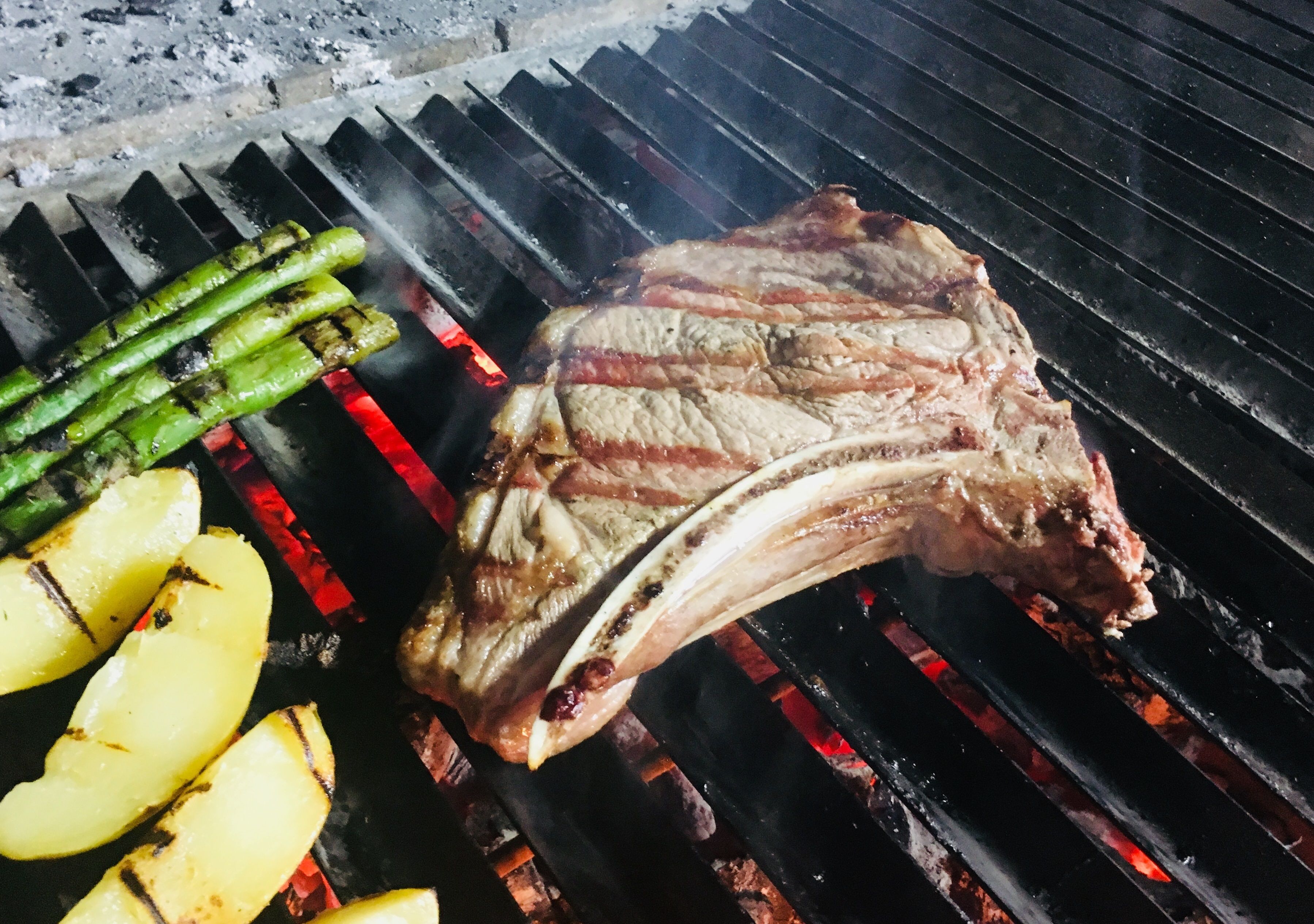 A steak and asparagus grilling on a barbecue.
