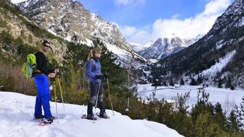 Dos personas en una montaña nevada con vistas a un valle y montañas al fondo.