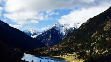 A mountainous landscape with a lake, snow-capped peaks, and forested areas.