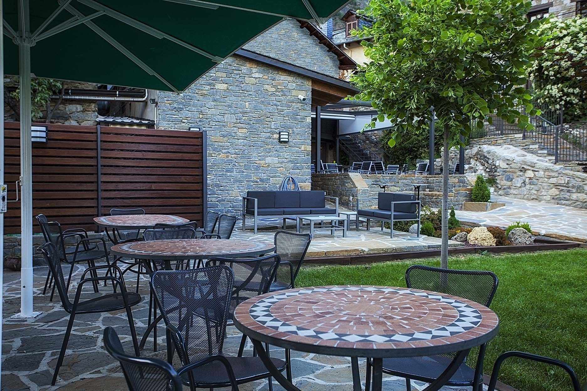 An outdoor patio with stone walls, metal chairs, and tables.