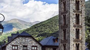 A stone building with a tower, surrounded by mountains and a clear sky.