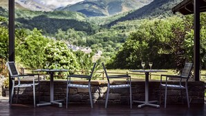 Een terras met een tafel en stoelen met uitzicht op een bergachtig landschap.