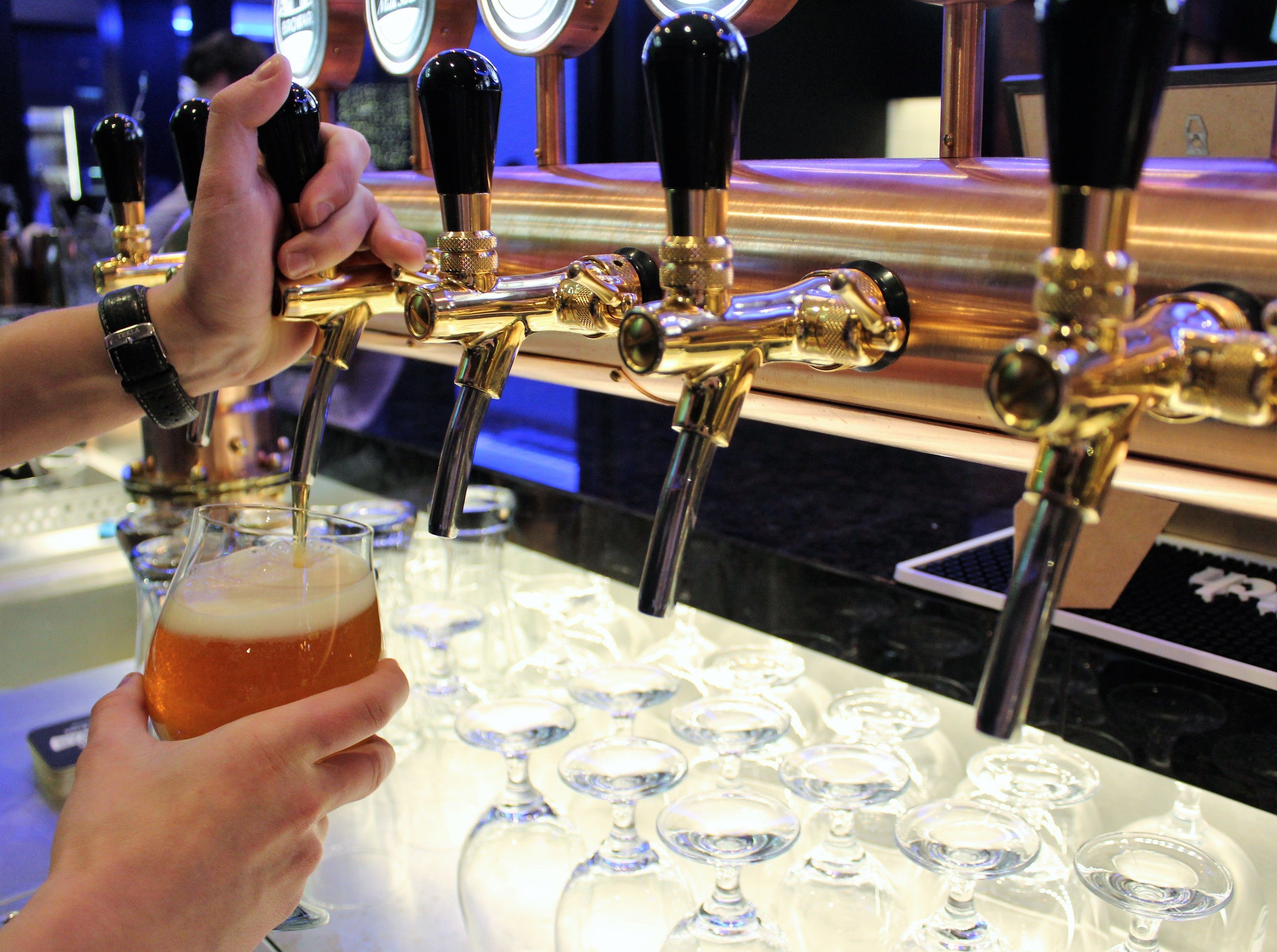 A bar with multiple taps and glasses on the counter.