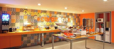 A buffet area with a colorful tiled wall, a buffet table with various food items, and a microwave in the background.