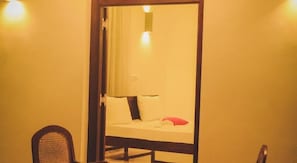 A room with a bed, a chair, and a door. - Villa Frangipani (Galle)