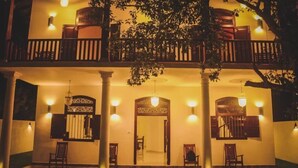 Un edificio de dos plantas con balcón, columnas y luces colgantes.
