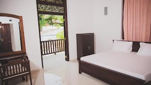Un dormitorio con cama, armario, espejo y puerta al balcón.