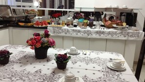 A buffet setup with various food items and a floral centerpiece on a table. - Hotel Pousada Alvorada (Brotas)