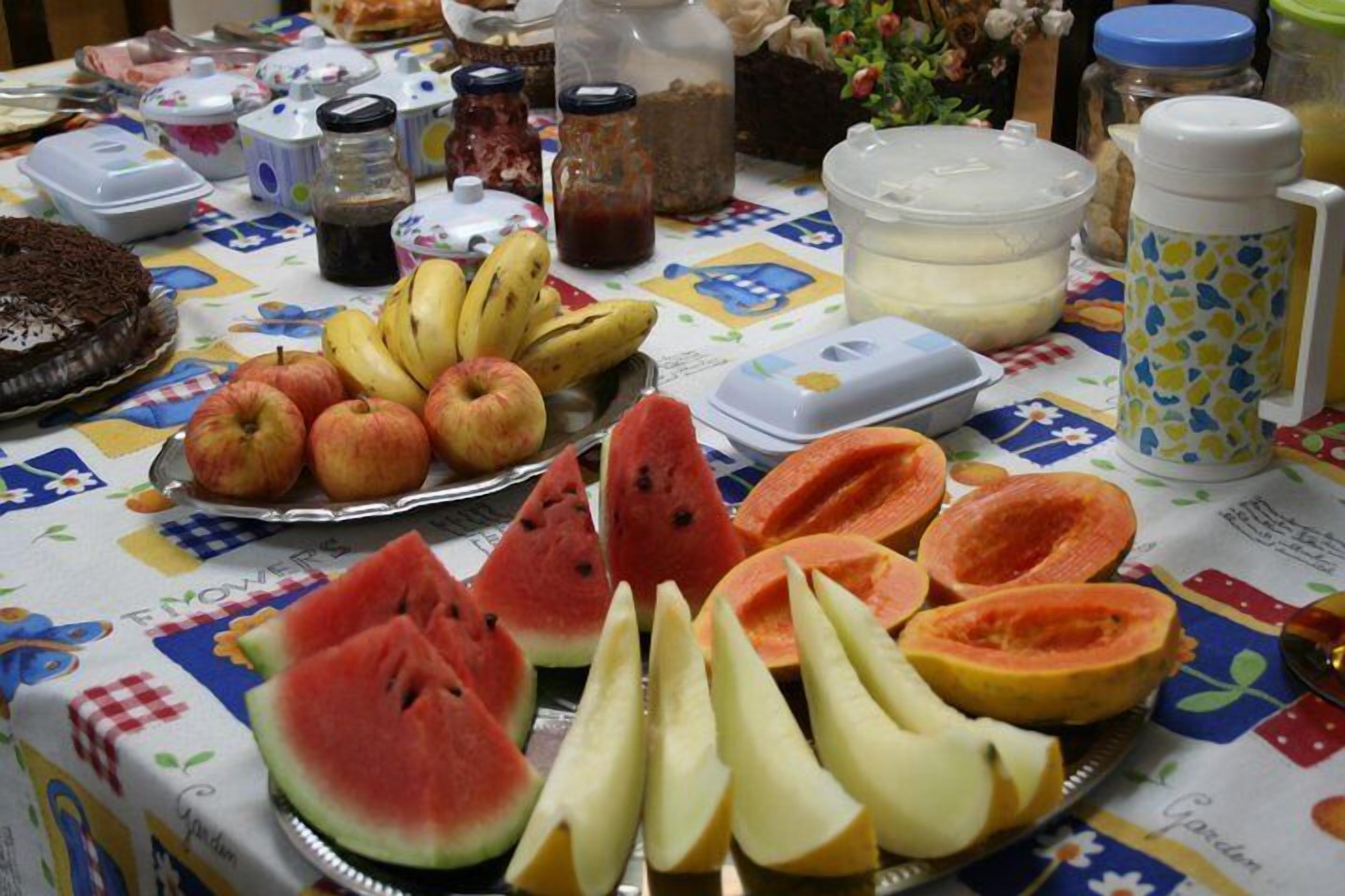A table with various fruits and a cake, along with several containers and jars.