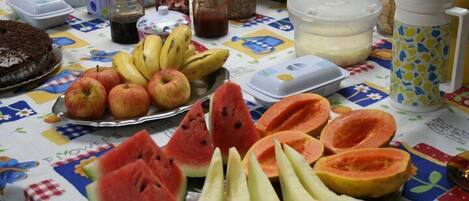 A table with various fruits and a cake, along with several containers and jars.