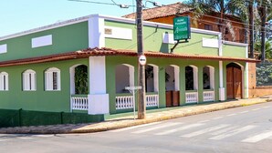 A green building with a sign for Hotel Pousado Alvorada. It has a tiled roof, multiple windows, and a balcony. - Hotel Pousada Alvorada (Brotas)