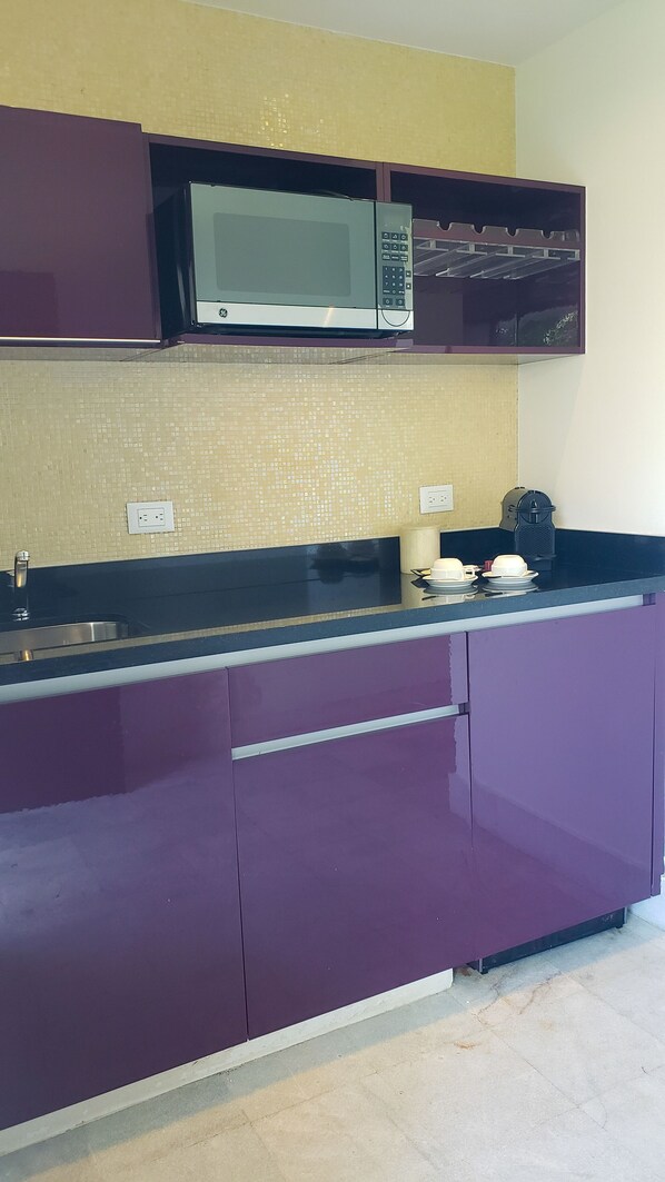 A kitchen with purple cabinets, a microwave, and a sink.