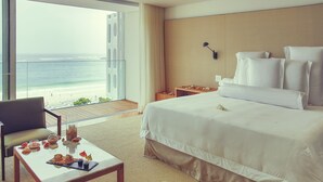 A hotel room with a bed, a chair, a table with breakfast items, and a view of the ocean. - Emiliano Rio (Rio de Janeiro)