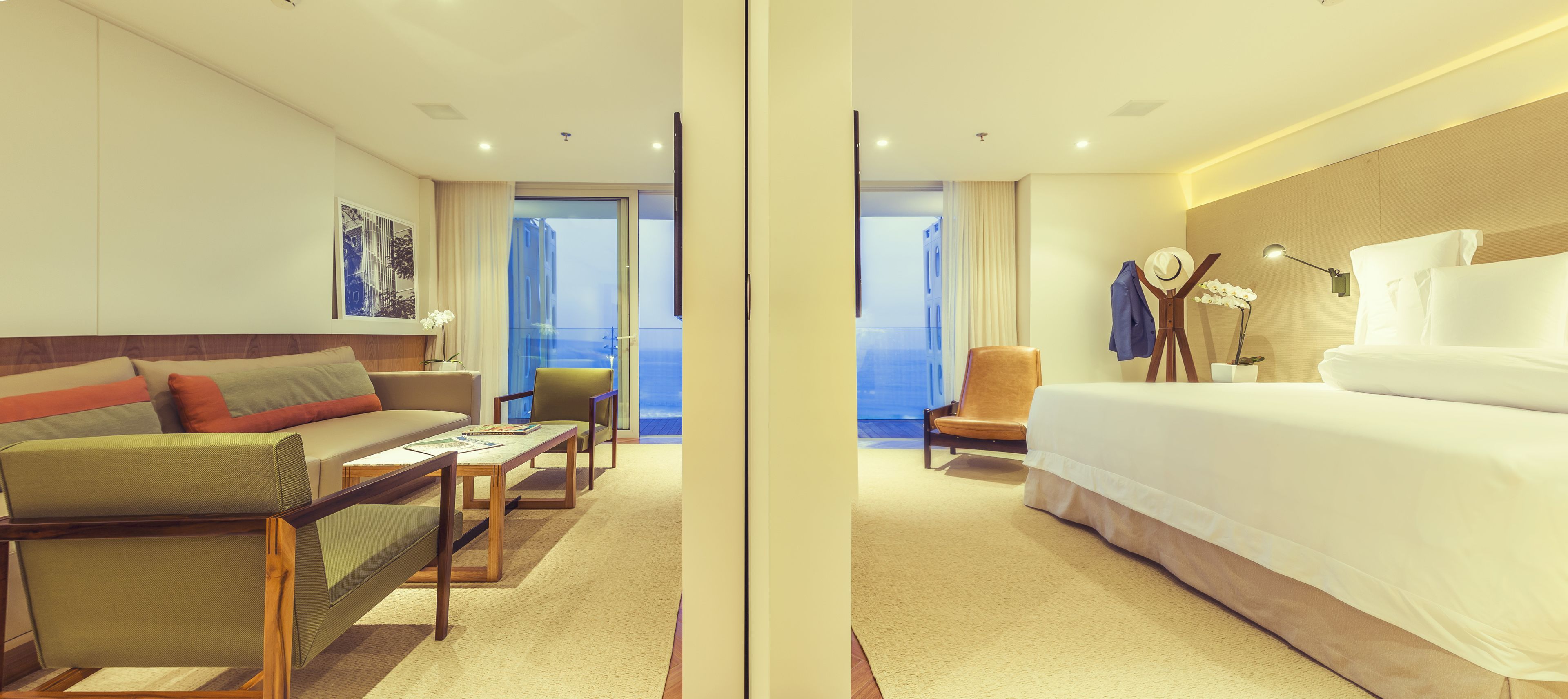 A hotel room with a bed, a sofa, a chair, a desk, and a view of the ocean.