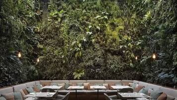 An indoor dining area with a lush green wall and multiple seating arrangements.
