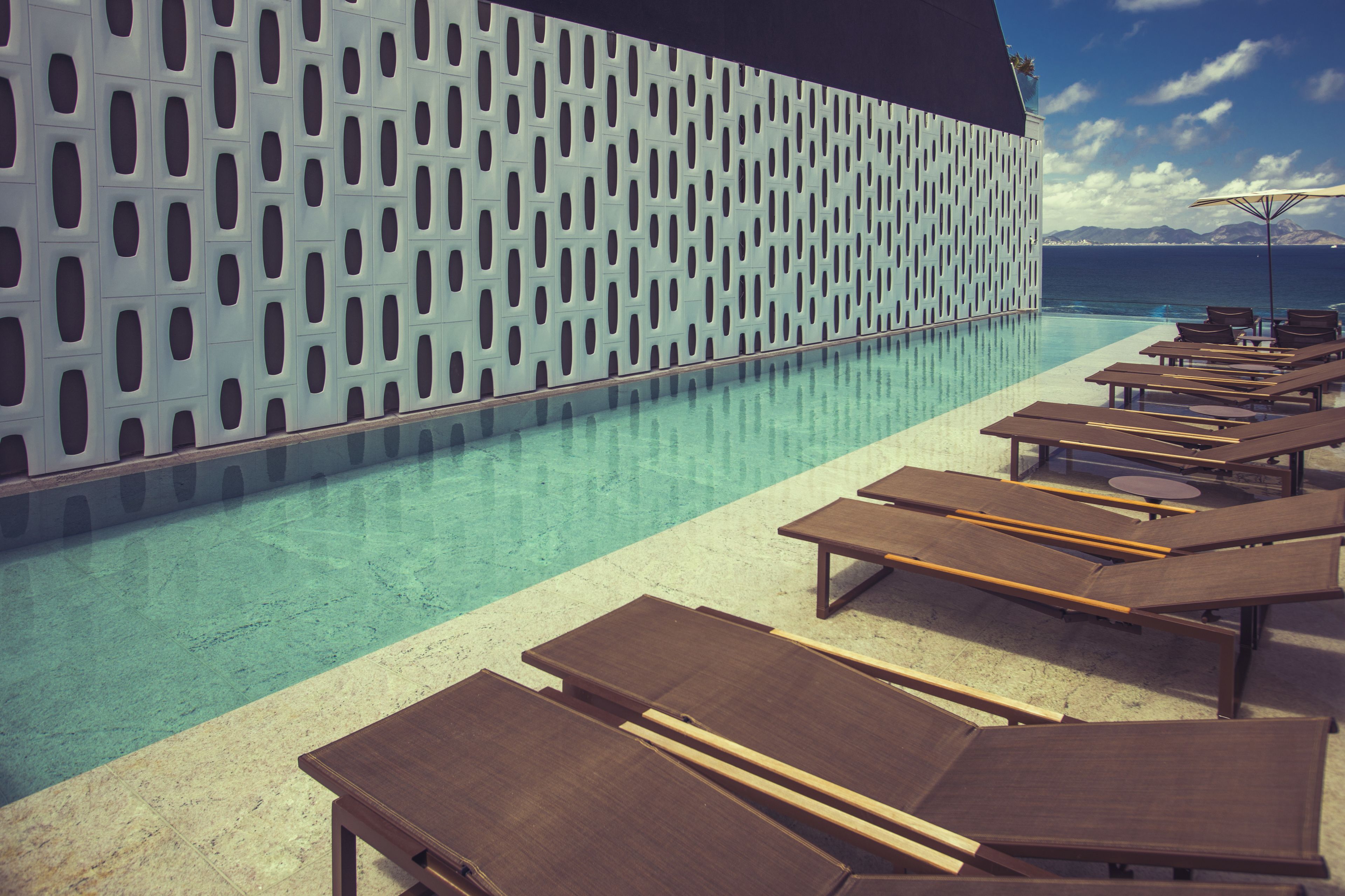 A poolside area with lounge chairs and a patterned wall.