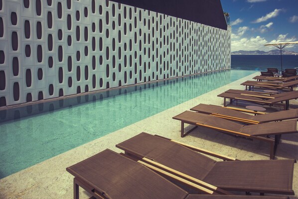 A poolside area with lounge chairs and a patterned wall.