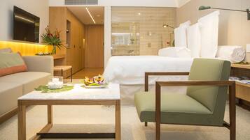 Una habitación de hotel moderna con cama, sofá, mesita de centro y escritorio.