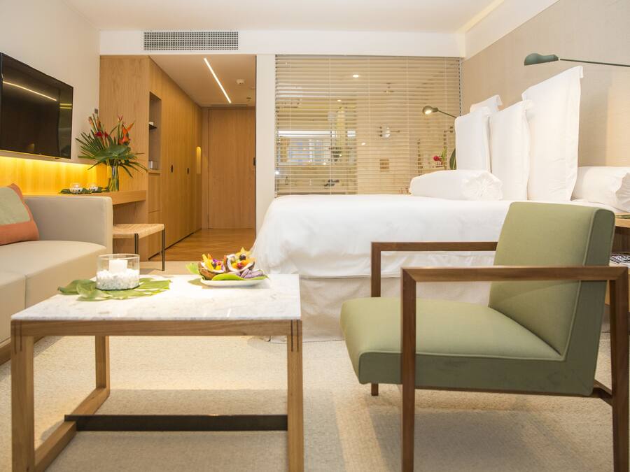 Una habitación de hotel moderna con cama, sofá, mesita de centro y escritorio.