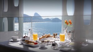 A breakfast table with a view of the ocean and mountains. - Emiliano Rio (Rio de Janeiro)