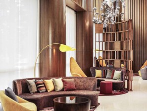 A modern living room with a sectional sofa, a coffee table, a floor lamp, and a decorative wooden bookshelf. - Mercure Kuala Lumpur Shaw Parade (Kuala Lumpur)
