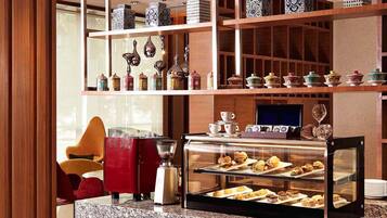 A hotel lobby with a coffee station, a TV, and shelves with decorative items.