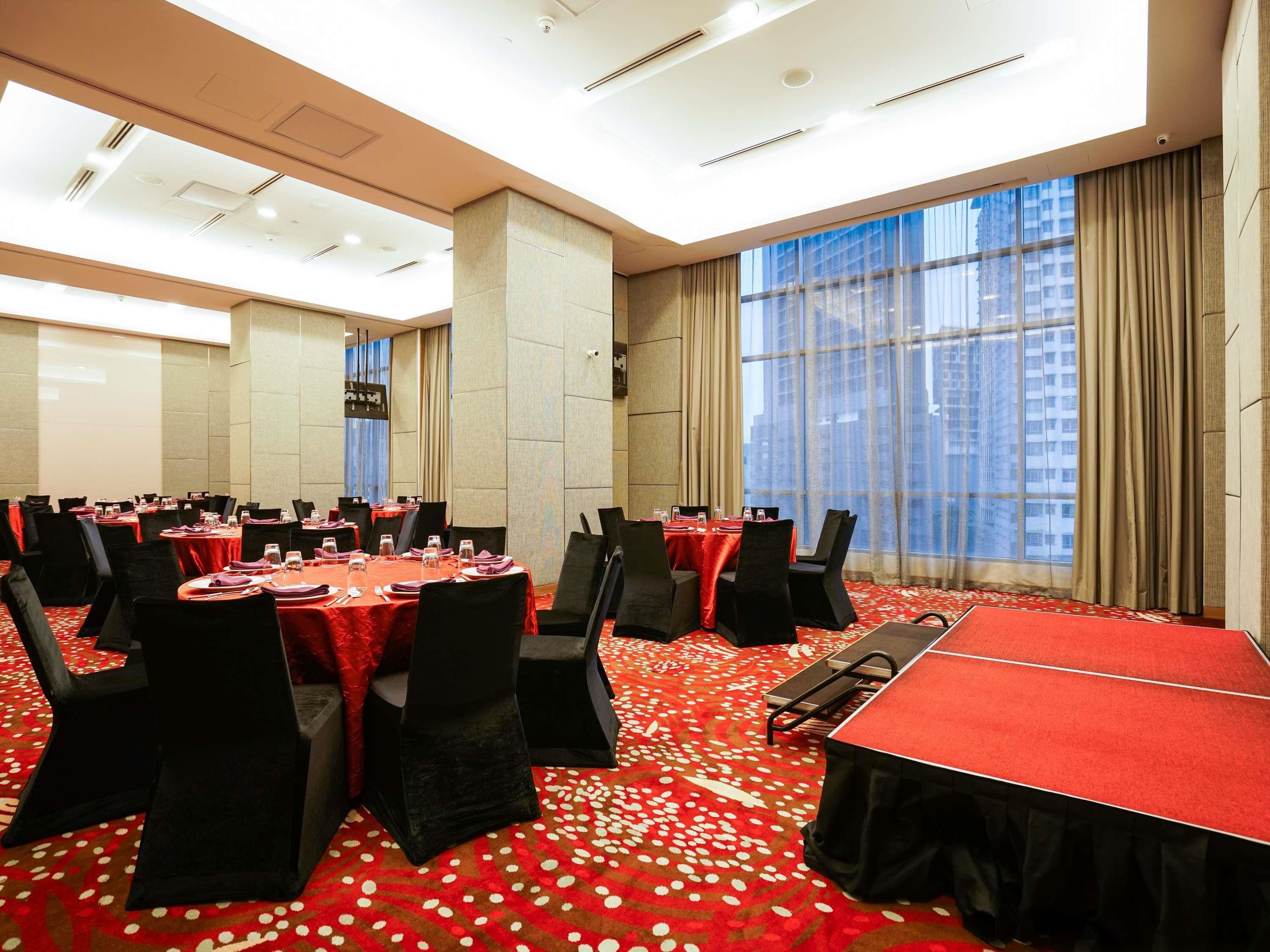 A conference room with round tables, black chairs, and a red carpet.