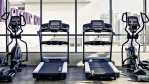 A gym with treadmills and elliptical machines, large windows, and a view of buildings. - Mercure Kuala Lumpur Shaw Parade (Kuala Lumpur)