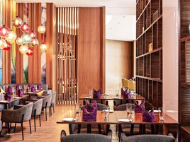 Un espace de restauration moderne avec un lambris en bois, plusieurs tables et des luminaires sphériques suspendus.