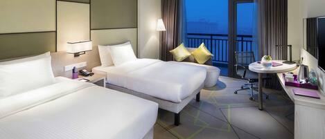 A hotel room with two beds, a desk, a chair, a TV, and a balcony with a view.