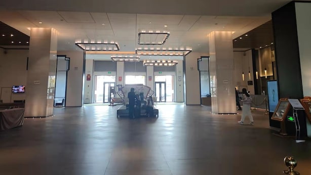 Un vestíbulo amplio con una zona de estar central, varios accesos y una recepción.