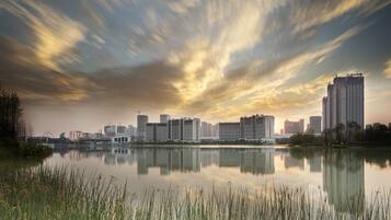 A city skyline reflected in a calm body of water with modern high-rise buildings.