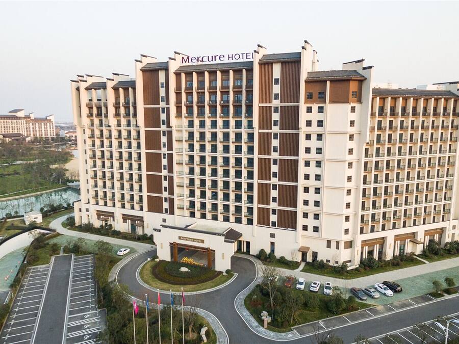 Ein hoch aufragendes Hotel mit modernem Design, das eine markante Eingangshalle und einen Parkbereich aufweist.