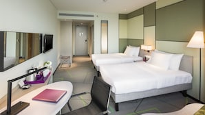 Habitación de hotel con dos camas, un escritorio con silla, televisión y baño a la vista.