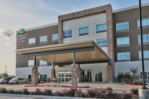 A Holiday Inn Express & Suites building with a covered entrance, multiple windows, and a fire lane. - Holiday Inn Express & Suites Houston East - Beltway 8 by IHG (Houston)