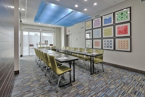 A conference room with a long table, chairs, and framed artwork on the wall.