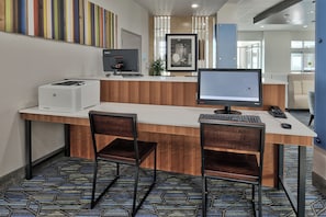 A hotel reception desk with a computer, two chairs, and a printer. - Holiday Inn Express & Suites Houston East - Beltway 8 by IHG (Houston)