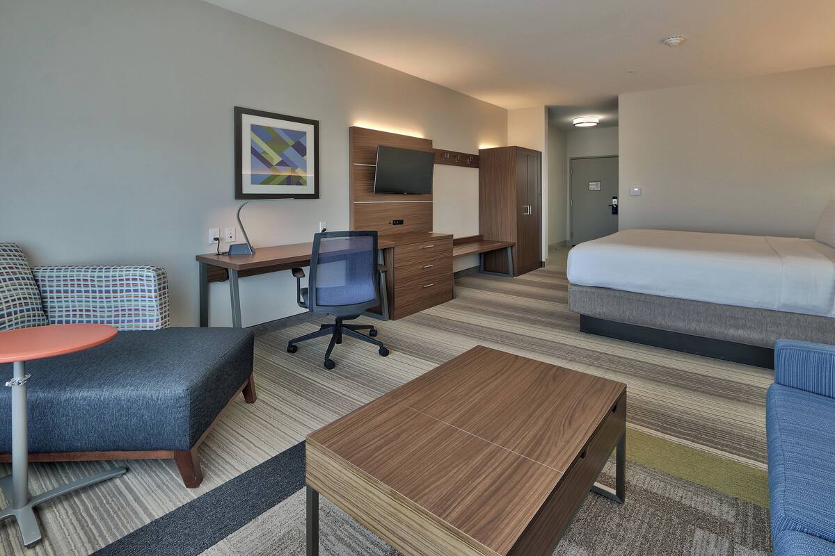 A hotel room with a bed, a desk with a chair, a small table, and a couch.