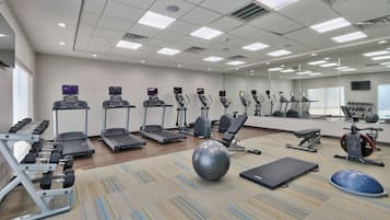 A gym with treadmills, elliptical machines, and free weights.