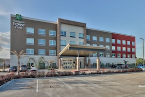 A Holiday Inn Express & Suites building with a covered entrance, parking lot, and a clear sky. - Holiday Inn Express & Suites Houston East - Beltway 8 by IHG (Houston)