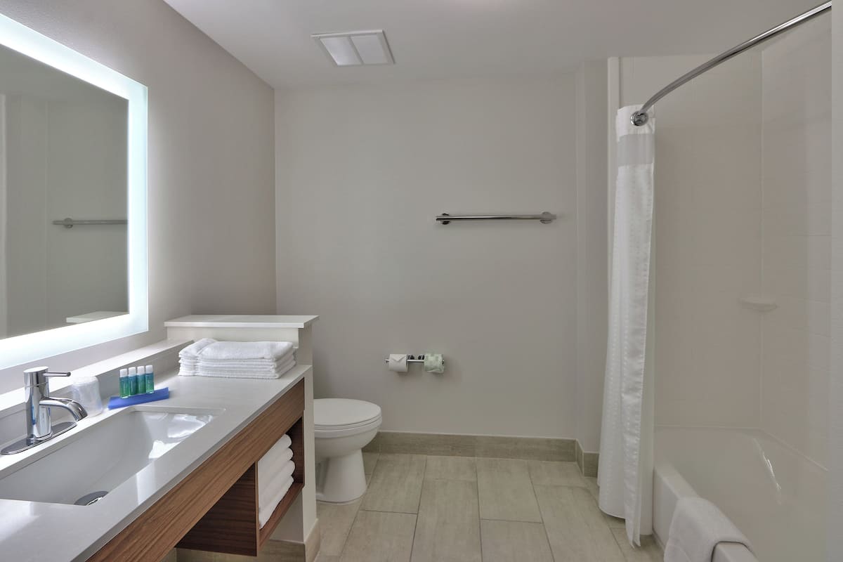 A modern bathroom with a sink, mirror, toilet, and shower.