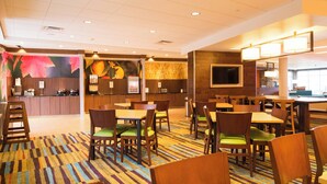 Eine Hotelhalle mit Empfangstresen, Sitzgelegenheiten und einem großen Bildschirm.