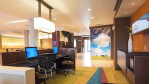 Eine moderne Hotelhalle mit einer Rezeption, Computern und einem farbenfrohen Teppich.